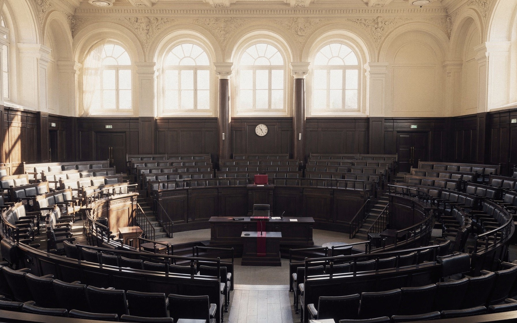 Empty parliamentary chamber in soft daylight, semicircular wooden benches